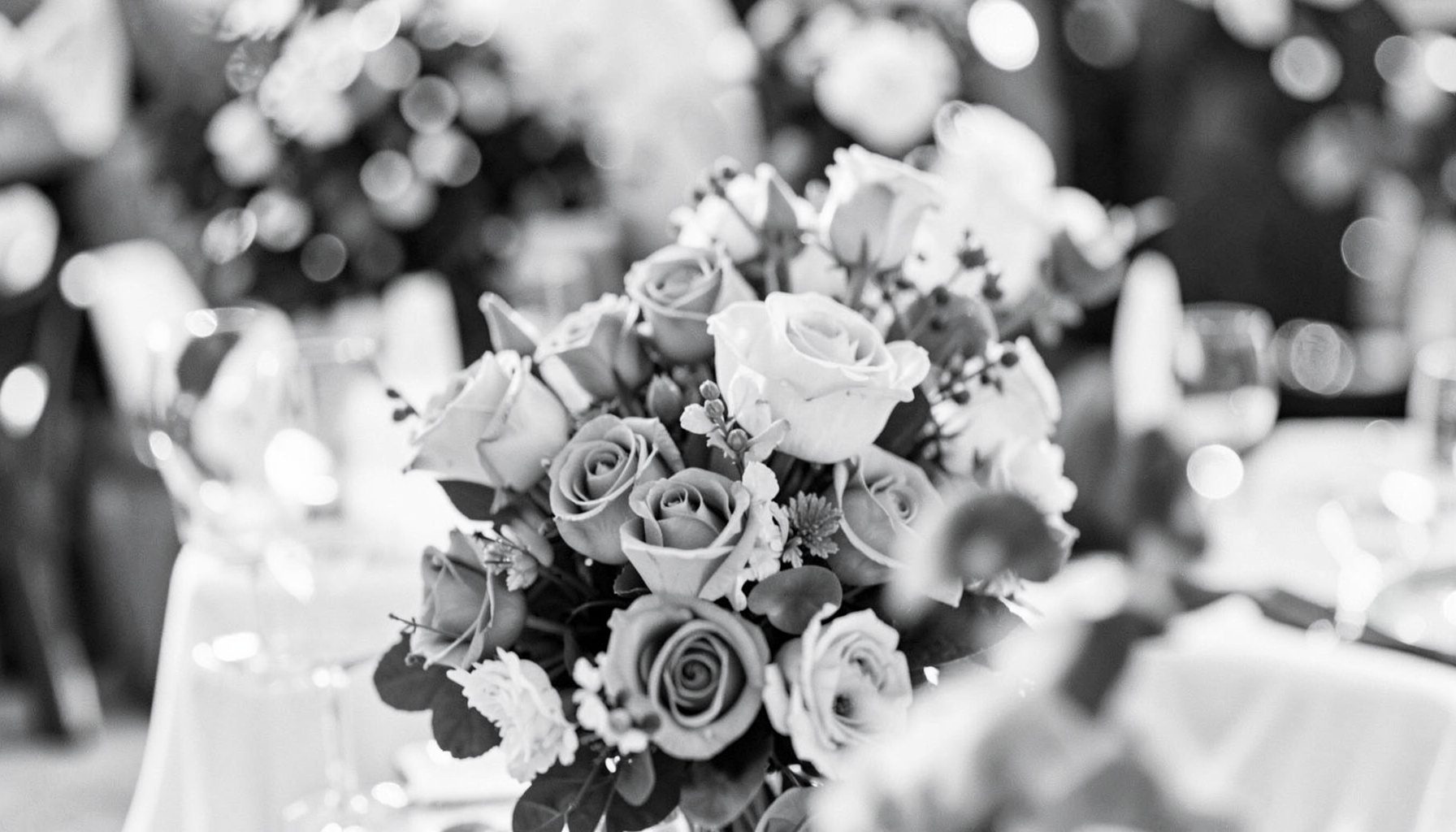 Duotone wedding reception detail with flowers and soft bokeh, muted rose and slate gray tones