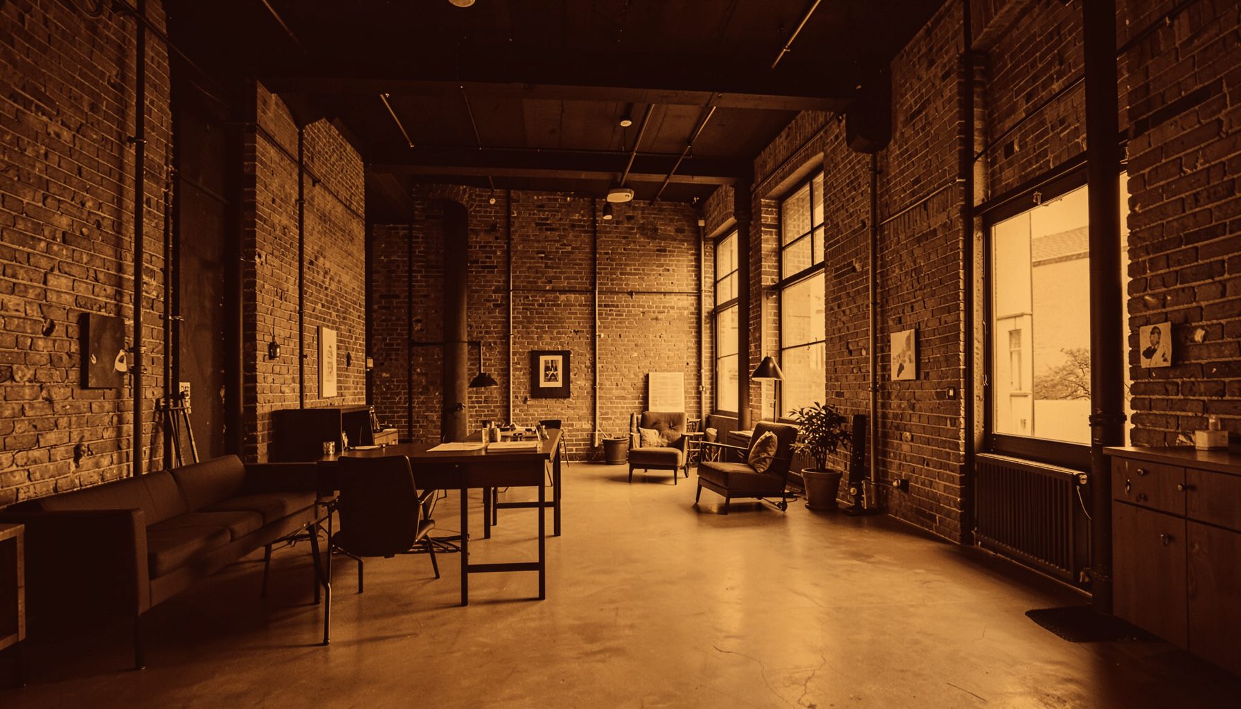 Duotone wide-angle interior of a modern loft space with exposed brick, warm amber and deep brown tones