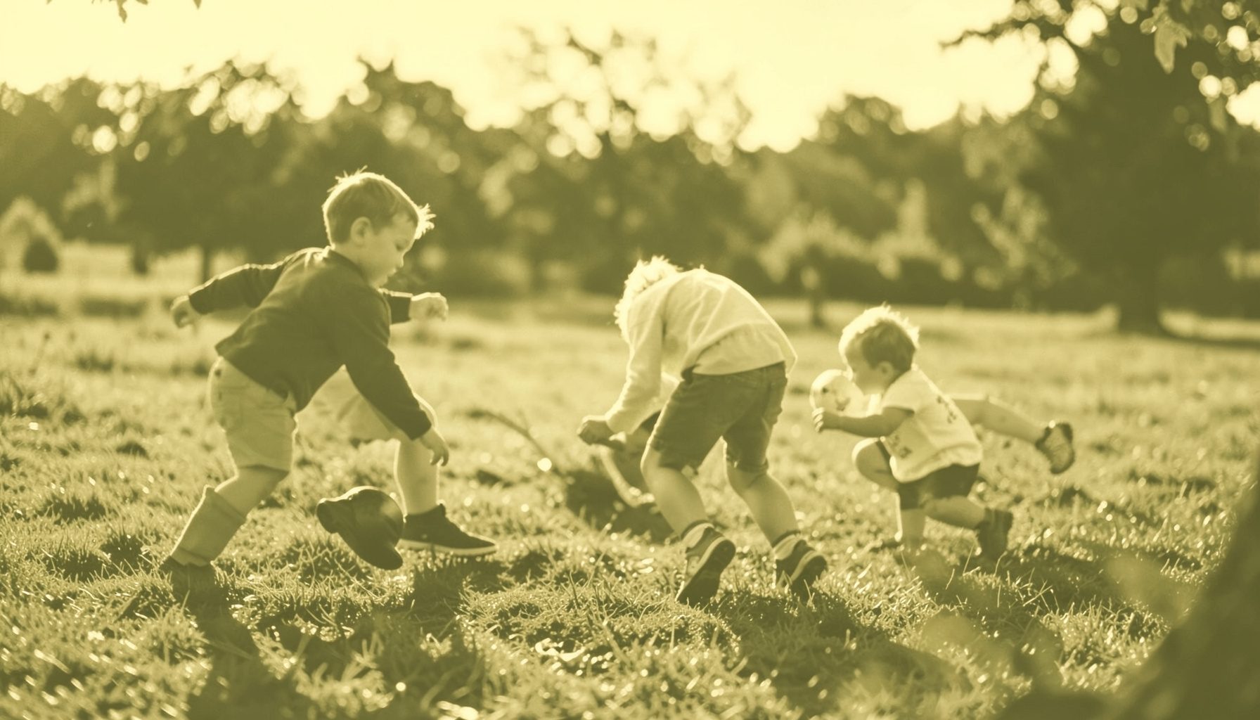 Duotone image of children playing outdoors, soft golden-hour light, warm honey and muted olive tones